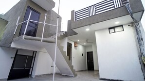 Un edificio moderno de dos pisos con una escalera, un balcón y una puerta.