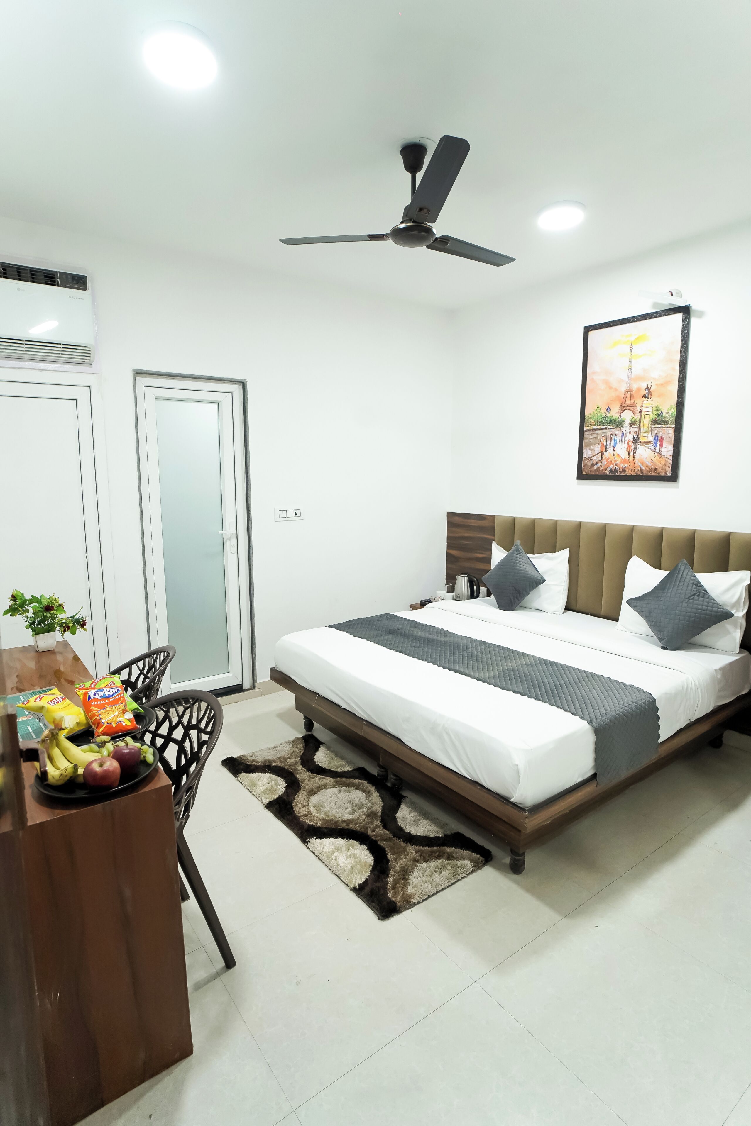 A bedroom with a bed, ceiling fan, and a painting on the wall.
