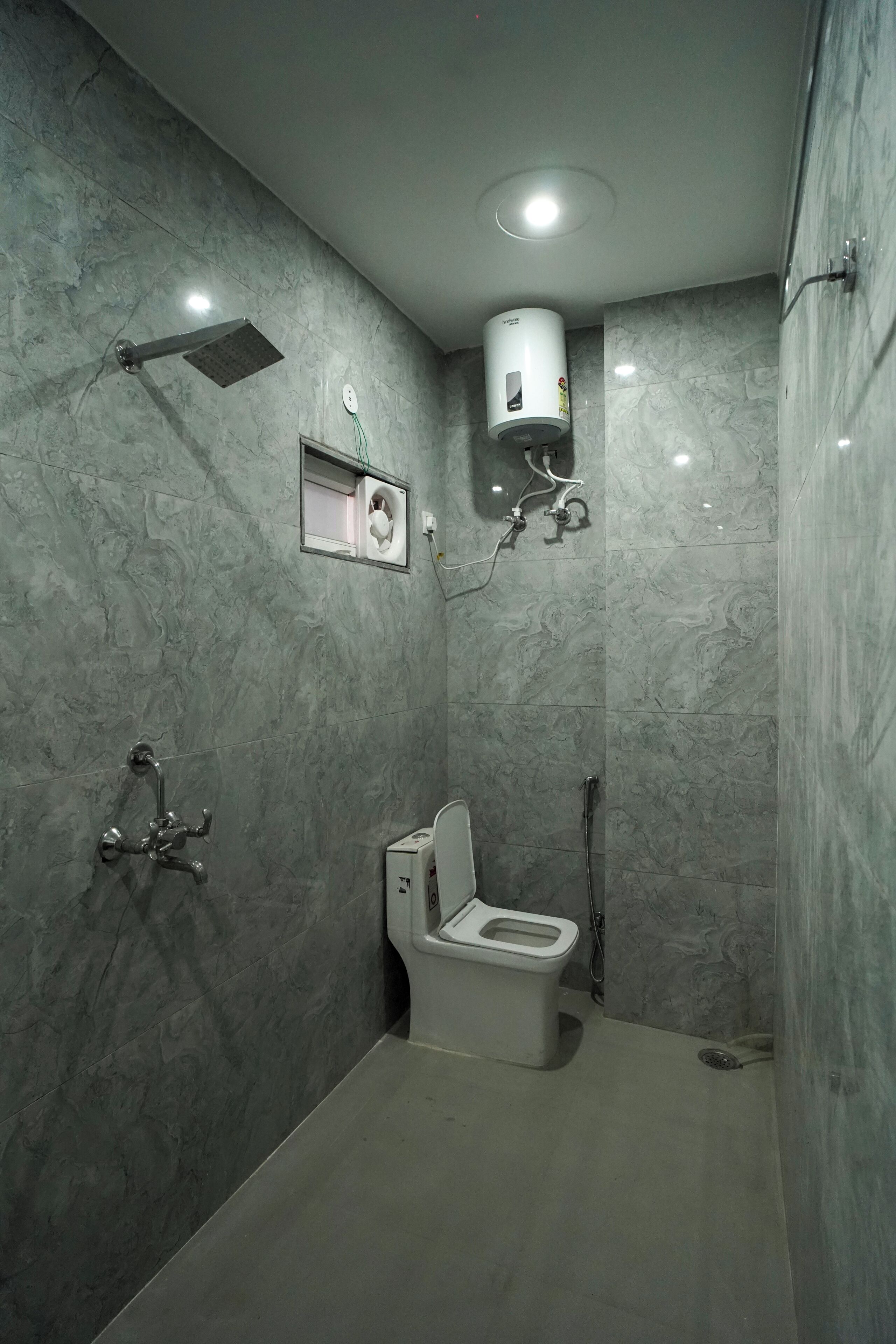 A bathroom with a toilet, shower, and a hand dryer.