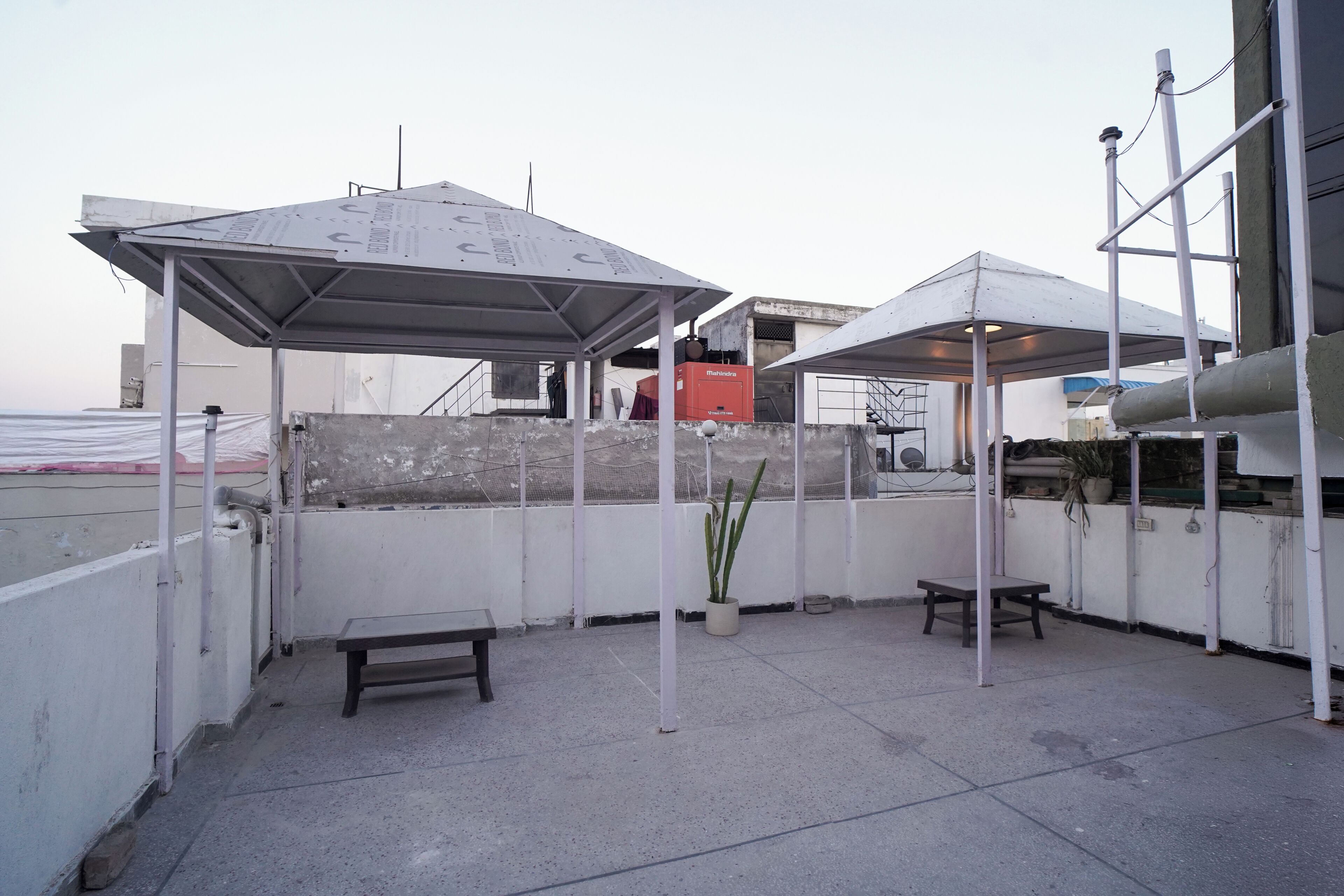 Una terraza en la azotea con dos zonas de estar cubiertas, una planta en maceta y una caja roja.