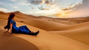 A desert landscape with sand dunes and a person sitting on a dune. - Desert Cactus Resort Jasialmer (Sam)