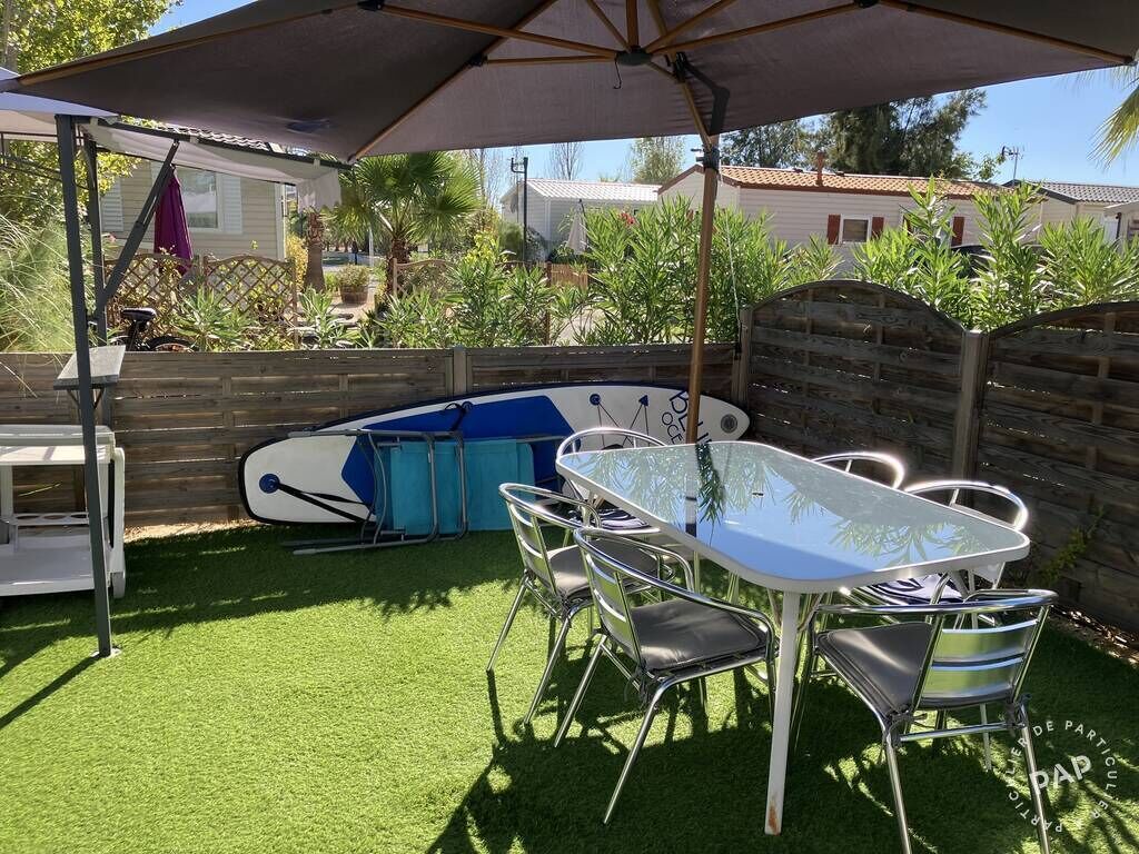 A patio with a table and chairs, a covered area, and a pool.