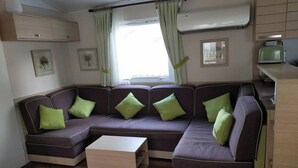 Ein modernes Interieur mit einem Ecksofa, einem kleinen Tisch und einer Küchenzeile.
