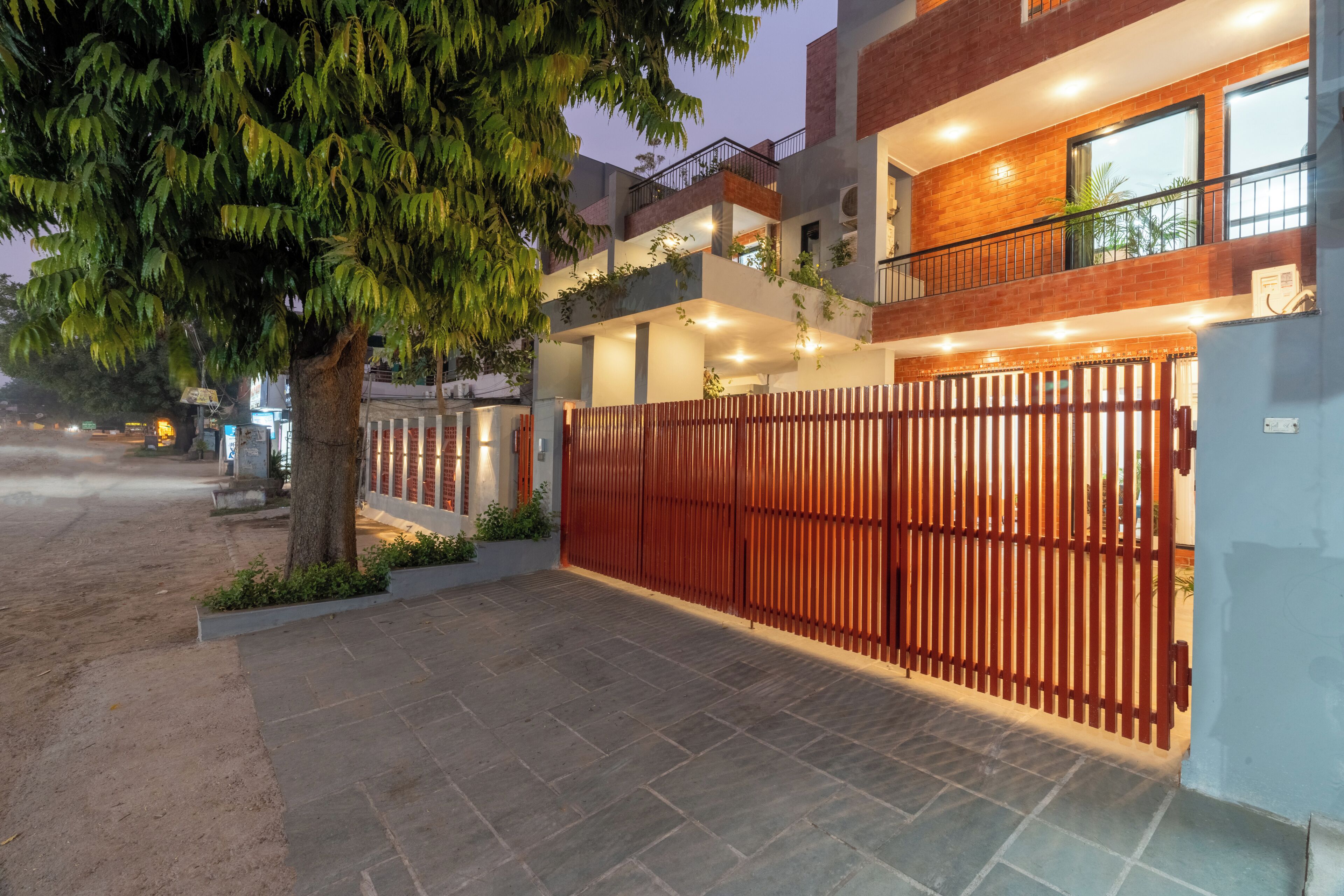 A multi-story building with a gated entrance, outdoor lighting, and a tree in the foreground.