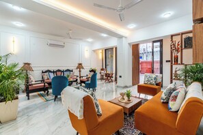 A modern living room with a sofa, chairs, a coffee table, and a dining area. - Alaya Stays Ramalaya 8BHK with Garden (Jaipur)