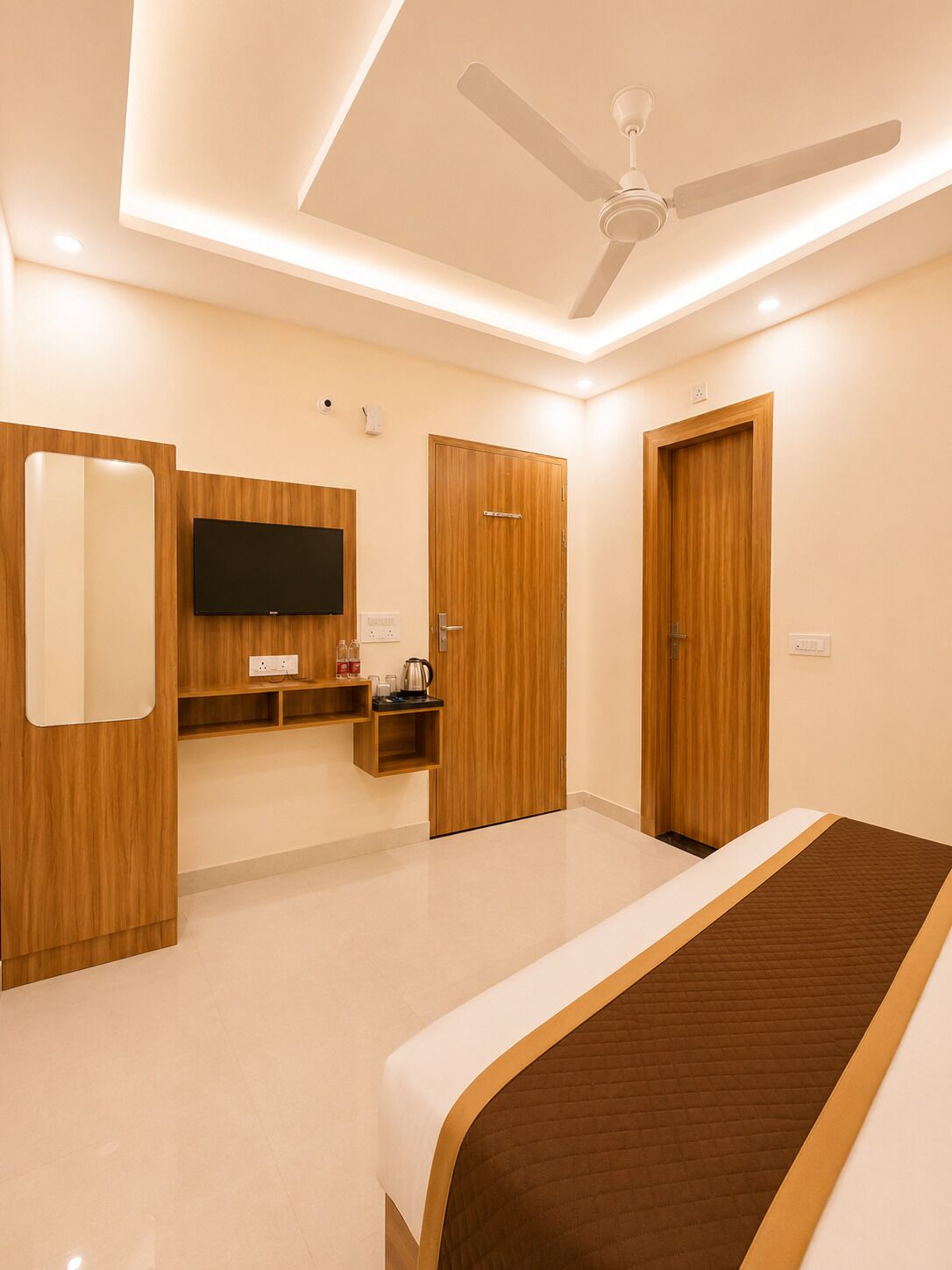 A bedroom with a bed, a ceiling fan, a TV, and wooden doors.