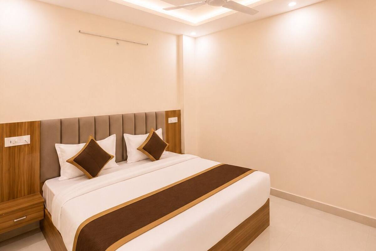 Una habitación de hotel moderna con una cama grande, ventilador de techo, luces empotradas y un cabecero de madera.