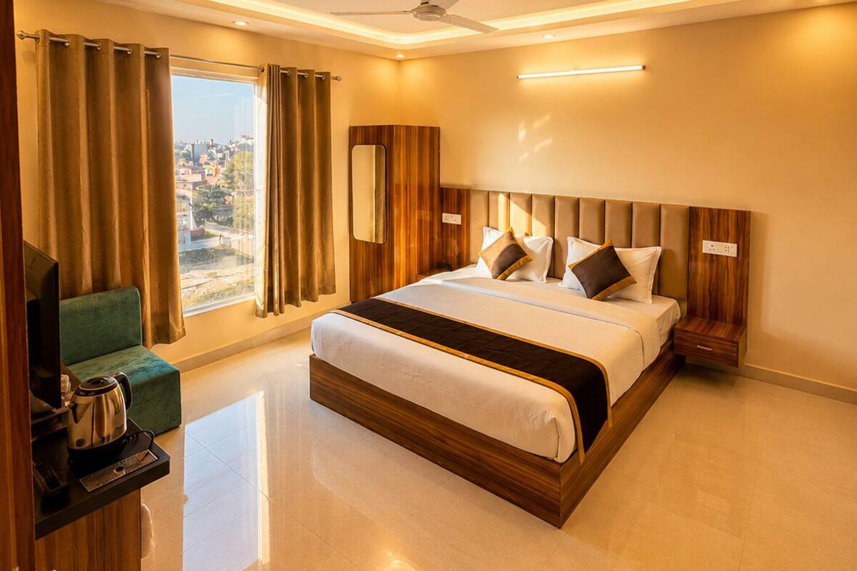 Habitación de hotel moderna con una cama grande, televisión de pantalla plana, cafetera y vista a la ciudad.