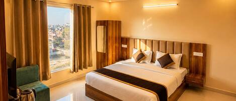 Habitación de hotel moderna con una cama grande, televisión de pantalla plana, cafetera y vista a la ciudad.