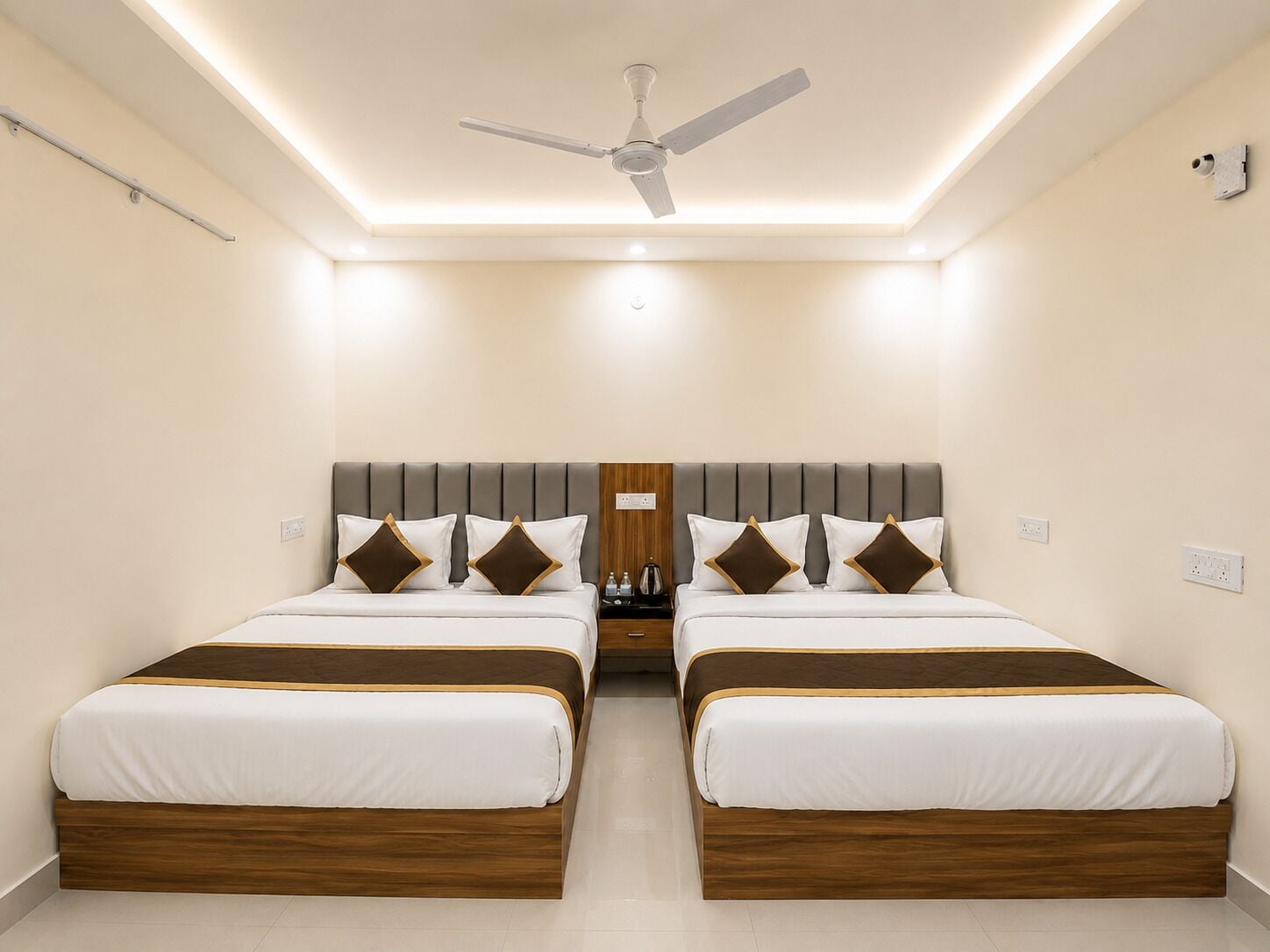 A hotel room with two beds, a ceiling fan, recessed lighting, and a wooden headboard.