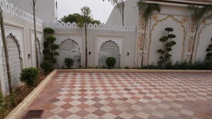 A courtyard with a checkered floor, ornate white walls, and decorative arches. - Neendar Heritage Resort (Jaipur)