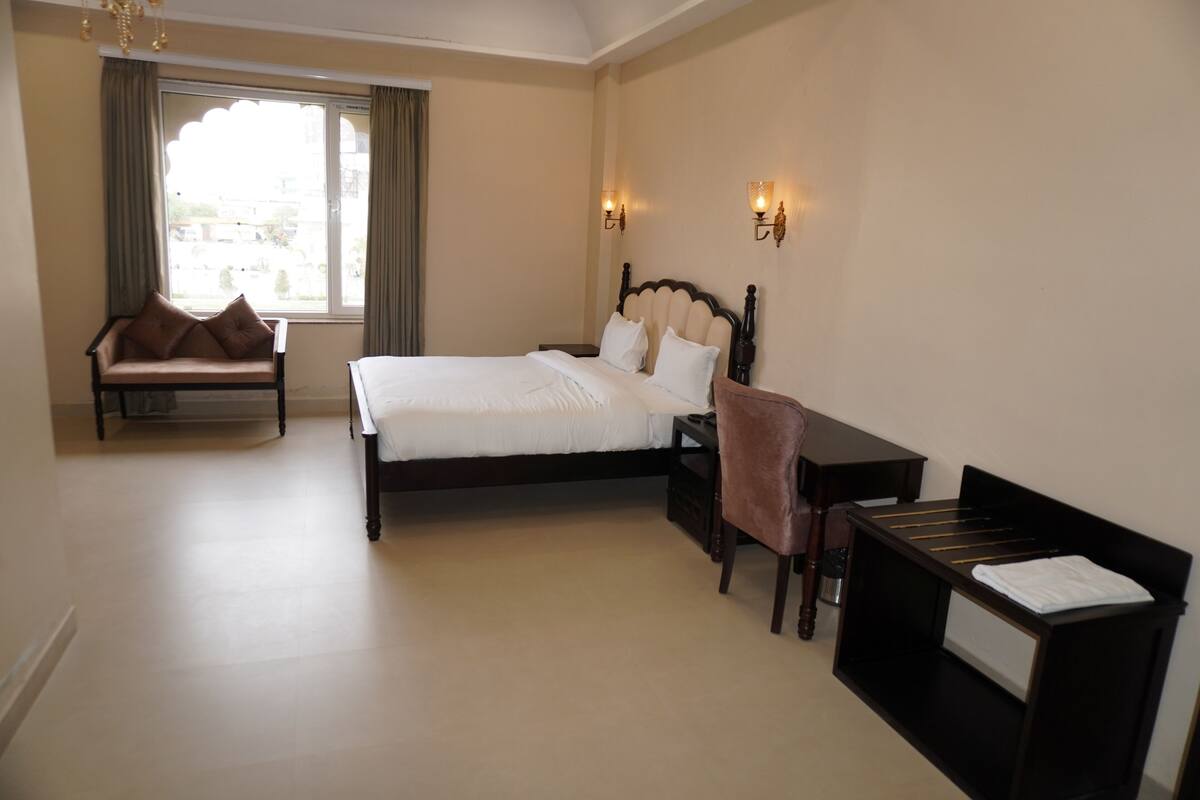 Una habitación de hotel con una cama grande, una zona de estar con sofá, un escritorio y una silla.