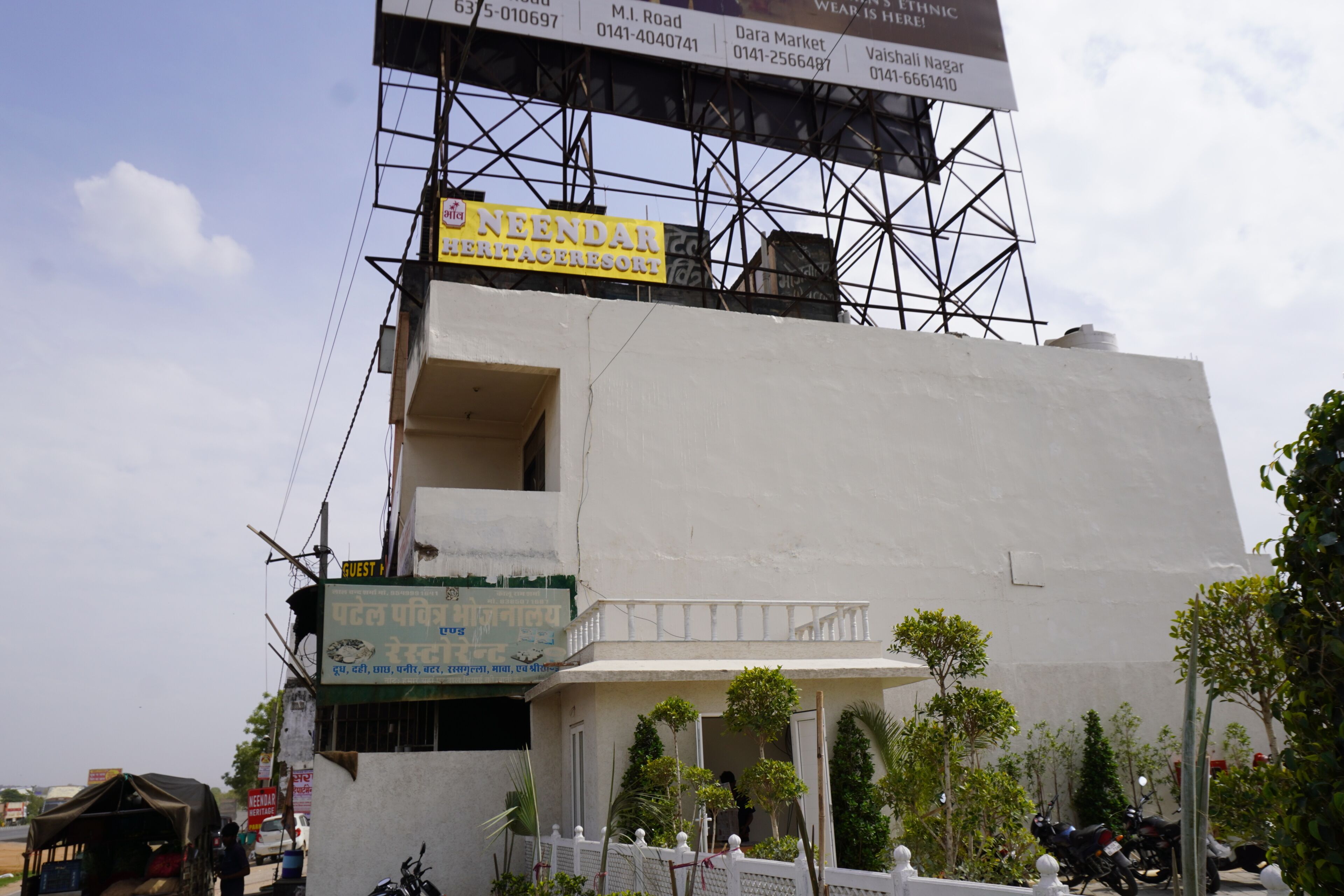 A building with a sign for 'NEENDAR HERITAGE RESORT' and a balcony with a railing.
