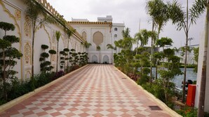A checkered pathway leading to a building with ornate architecture and a view of a body of water. - Neendar Heritage Resort (Jaipur)