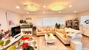 A living room with a sofa, coffee table, TV, and decorative plants.