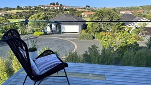 A balcony with a chair, a view of a residential area, and a garage.