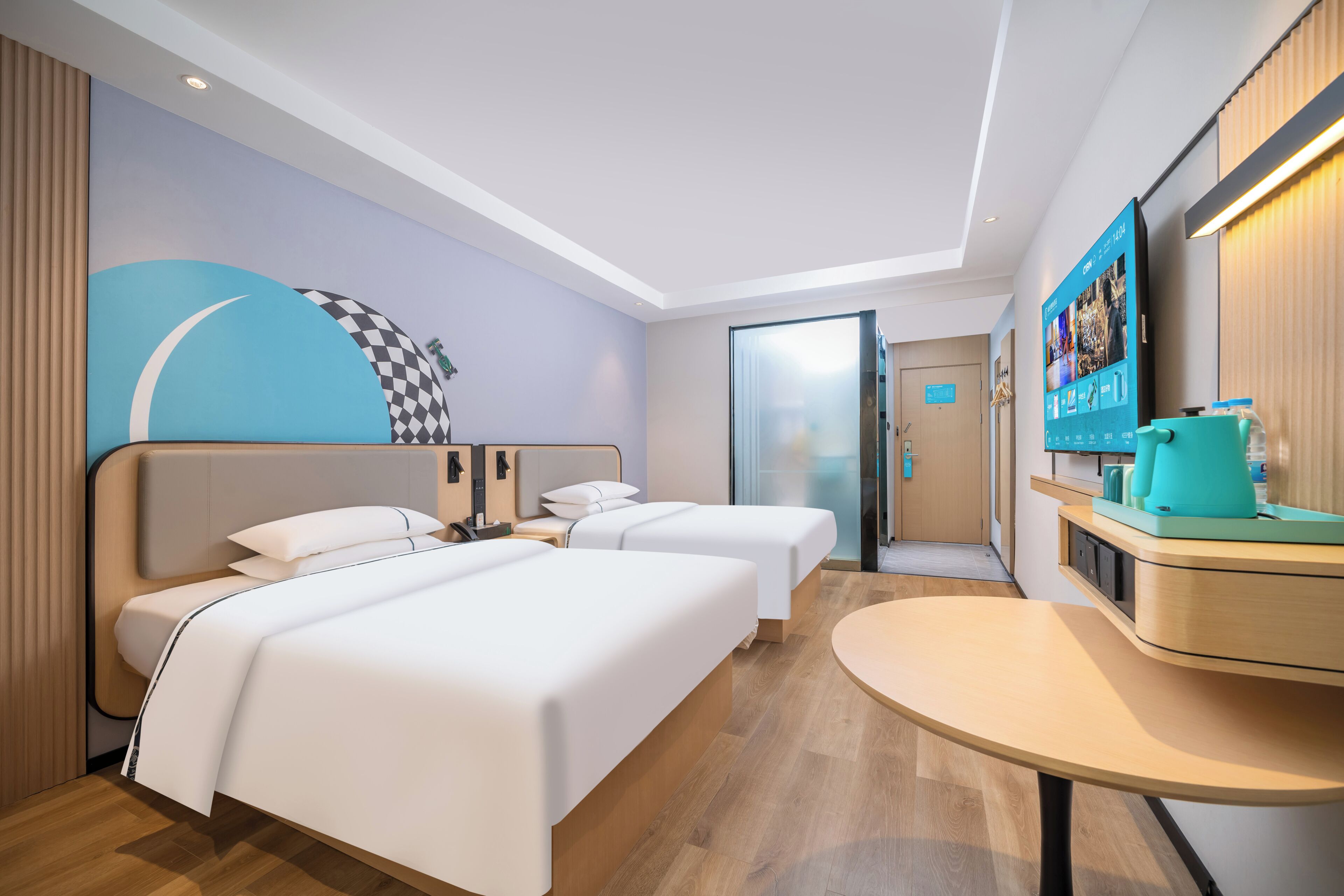 A hotel room with two beds, a small table, a TV, and a wall-mounted screen.
