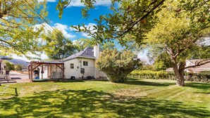 A house with a covered porch, a lawn, and a tree with fruit.