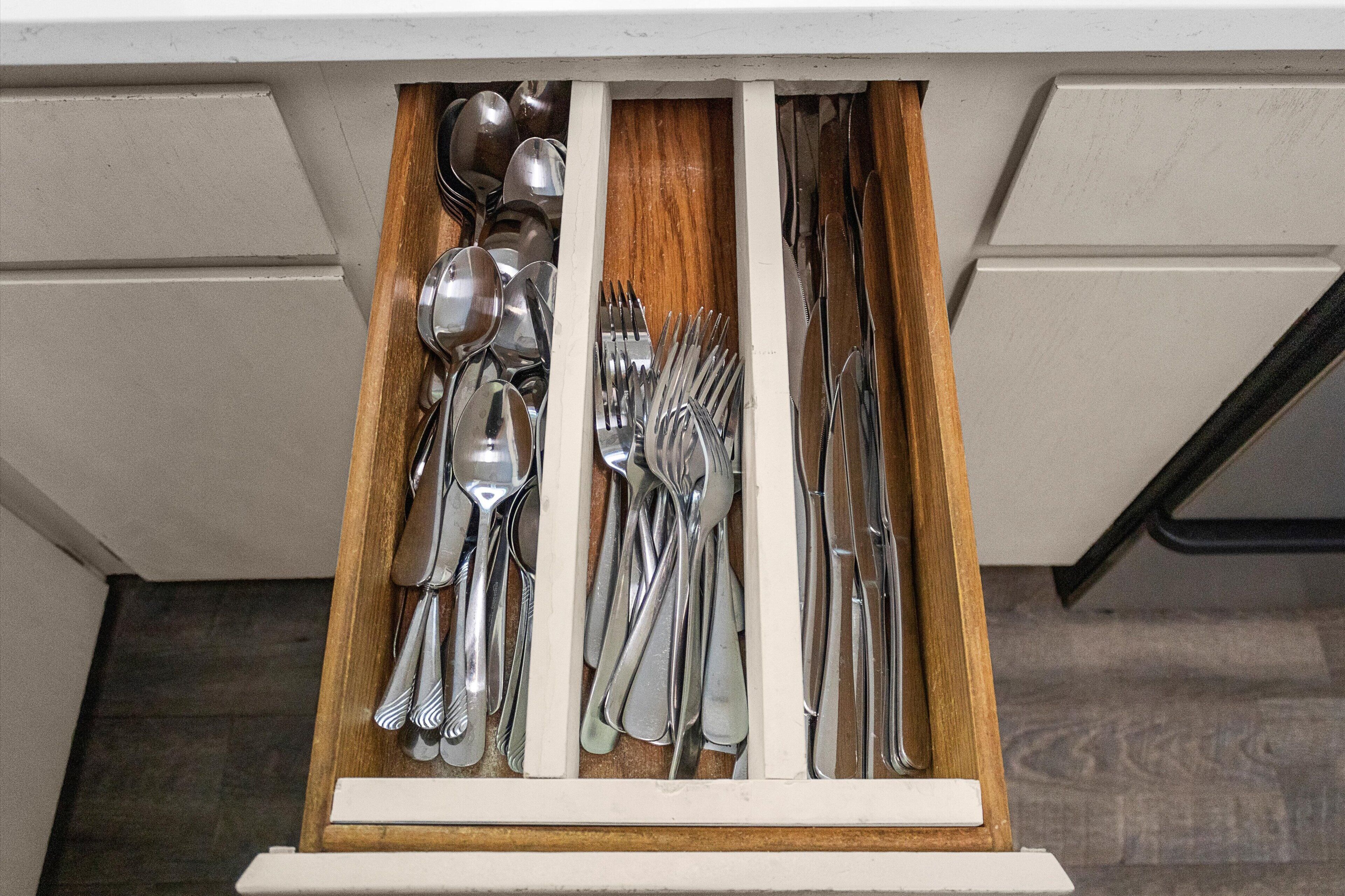 Un cajón con varios utensilios de cocina, como cucharas, tenedores y cuchillos.