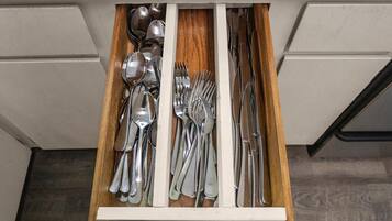 Un cajón con varios utensilios de cocina, como cucharas, tenedores y cuchillos.