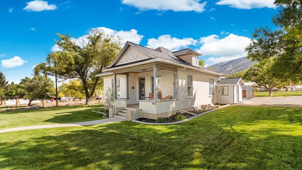 A two-story house with a covered porch, a small attached garage, and a well-maintained lawn.