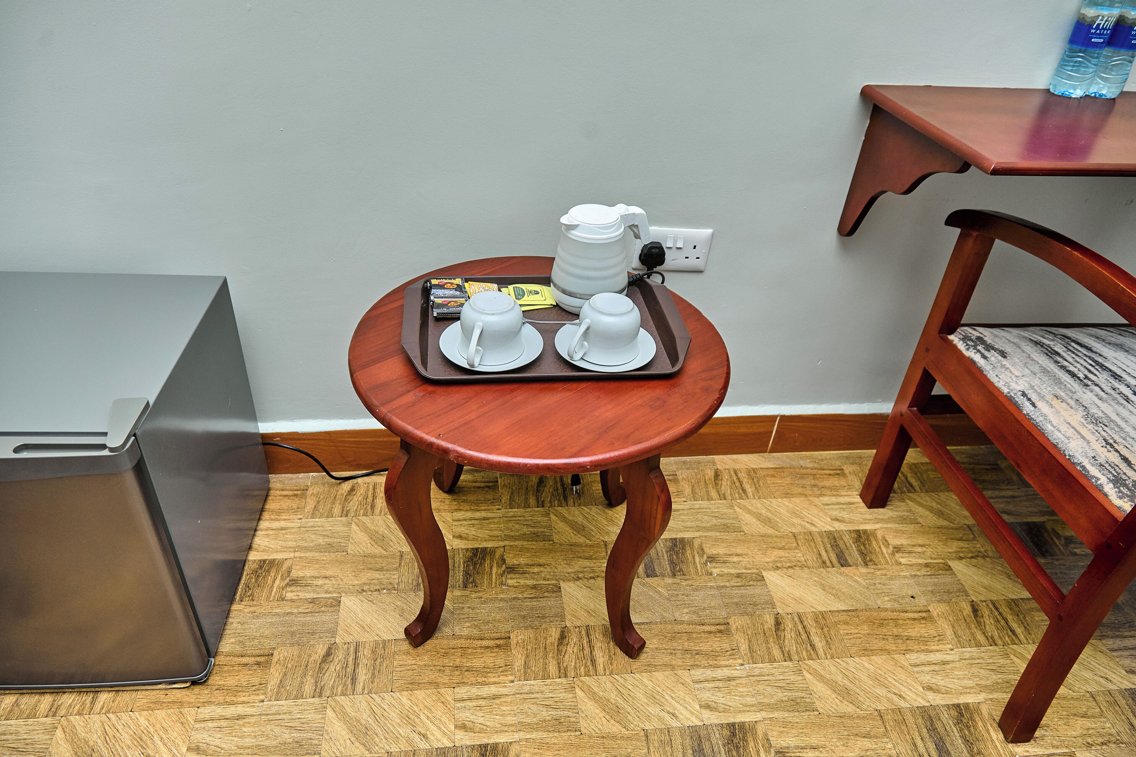 A compact room with a small wooden table, a metal cabinet, and a wooden chair.