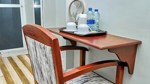 Un coin repas avec une table et une chaise en bois, un plateau sur lequel se trouve une tasse blanche et deux bouteilles d’eau.