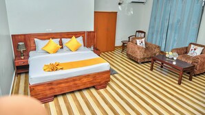 Une chambre d’hôtel avec un lit en bois, un canapé, une table basse, une armoire et un rideau.