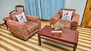 Une pièce avec deux fauteuils marron, une table basse en bois et un parquet à rayures.