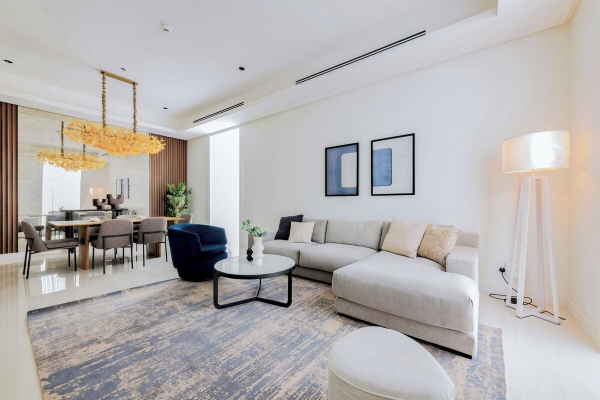 A modern living room with a dining area, a sofa, a coffee table, and a lamp.