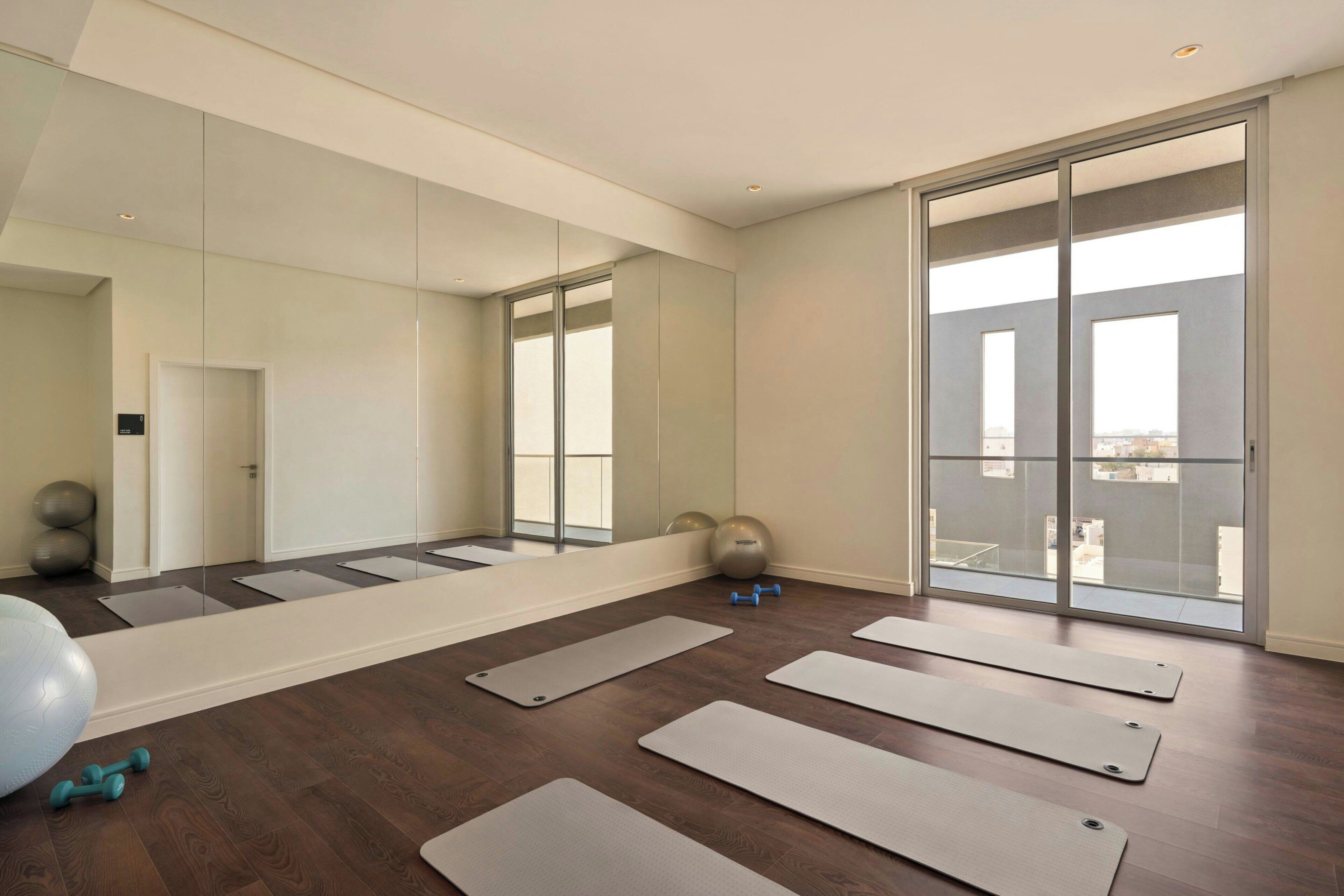 A spacious room with large windows, exercise mats, and fitness equipment.