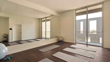 A spacious room with large windows, exercise mats, and fitness equipment.