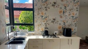 A kitchen with a window, a sink, a kettle, and a stove. - The Gracewood Sanctuary - Your Peaceful Hideaway (Johannesburg)