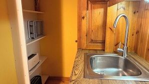Een keuken met houten kasten, een roestvrijstalen spoelbak en ingebouwde planken.