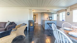 Una cocina moderna con una isla central, un comedor con una mesa redonda y una zona de estar acogedora con chimenea.