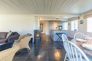 Eine moderne Küche mit Kochinsel, einem Essbereich mit rundem Tisch und einer gemütlichen Sitzecke mit Kamin.