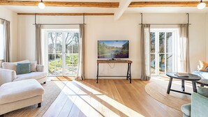 Un ampio soggiorno con parquet, un divano, un tavolino da caffè e un quadro appeso al muro.