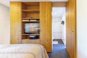 A bedroom with a bed, wooden wardrobe, television, and a view into the bathroom. - Haus Ziegelmacher - Lütt in Rodenäs for up to 2 persons (Rodenäs)