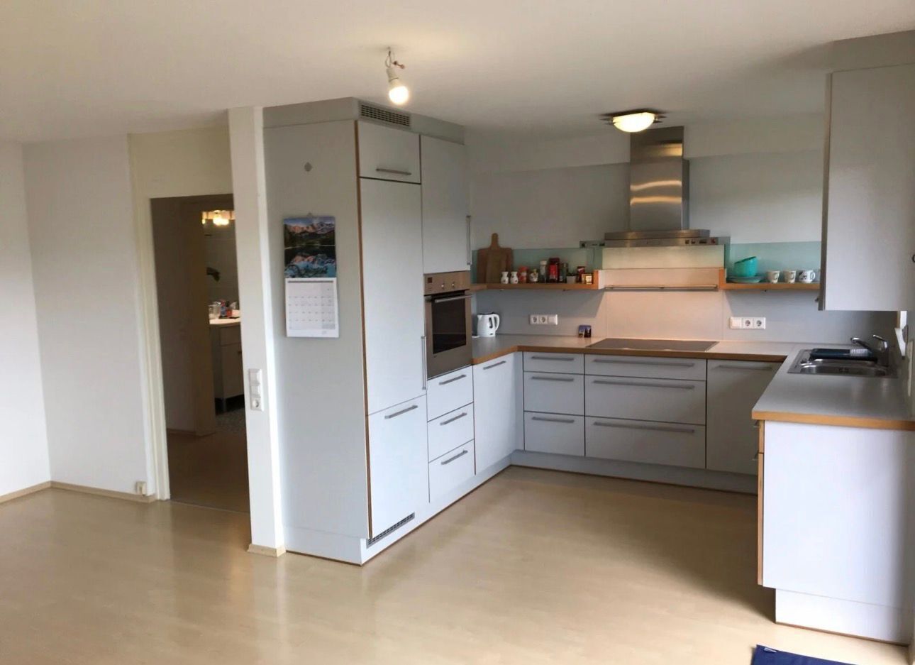 A modern kitchen with white cabinets, a built-in oven, and a countertop.