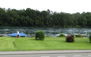 A lakeside view with a grassy area, a small structure, and boats docked.
