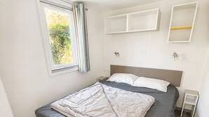 Ein Schlafzimmer mit einem Bett, einem Vorhangfenster und Einbauschränken.