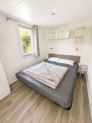 Ein Schlafzimmer mit einem Bett, einem Vorhangfenster und Einbauschränken.
