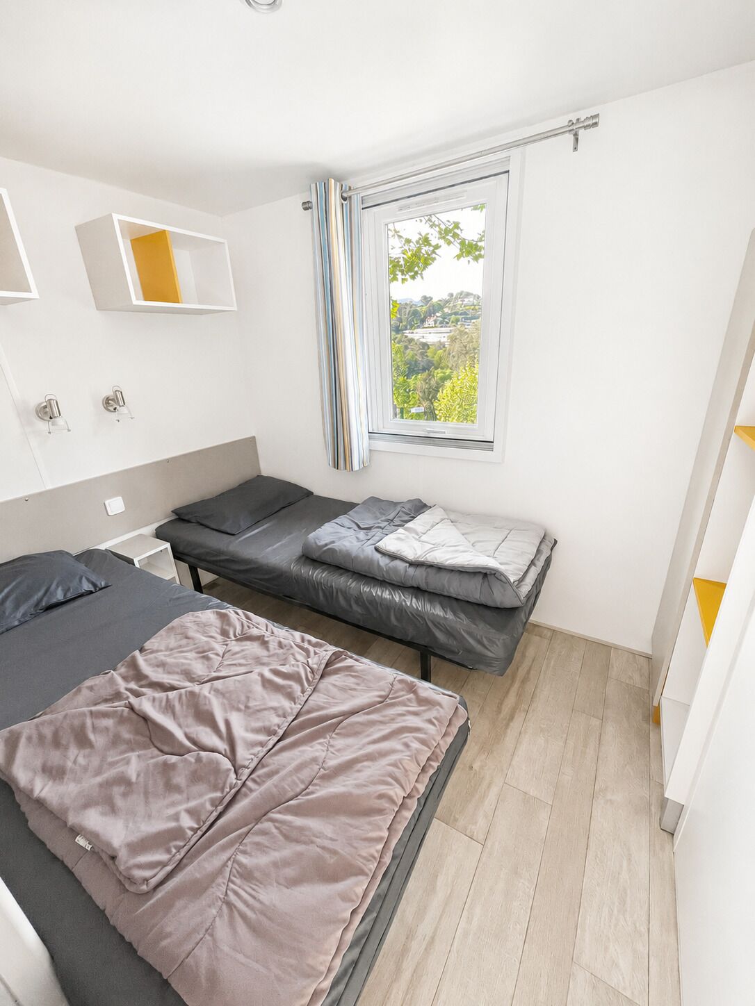 Un dormitorio moderno con cama, una mesita, una ventana con cortinas y vistas al exterior.