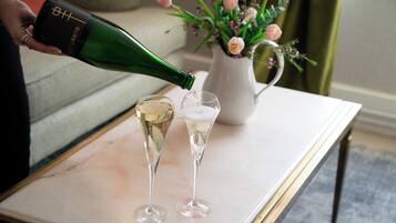 A person pouring champagne into two glasses on a marble table.