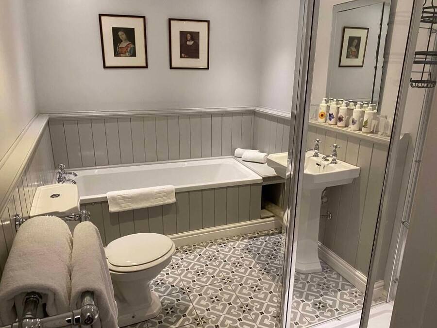 A bathroom with a bathtub, toilet, sink, and shower. There are framed pictures on the wall.