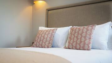 A neatly made bed with patterned pillows, a headboard, and a wall-mounted light fixture.