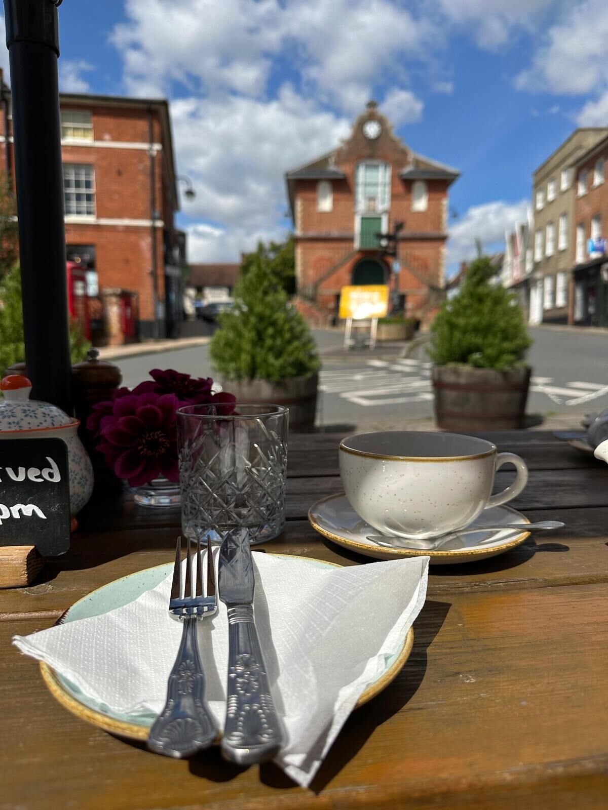 A table with a cup, saucer, glass, and cutlery, with a sign indicating 'served 11pm'.