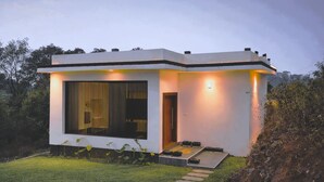 A modern house with a large window, a door, and a small outdoor seating area.
