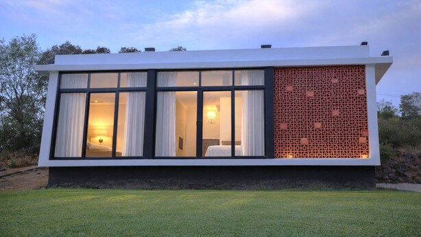 A modern building with large windows, a patterned wall, and a well-maintained lawn.