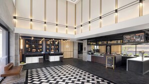 Een moderne lobby met een centraal zitgedeelte, een bar en een receptiebalie.